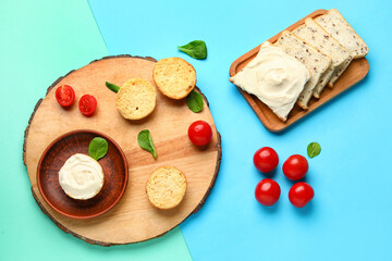 Wooden board of tasty toasts with cream cheese on blue background