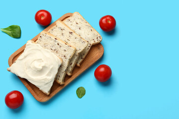 Wooden board of tasty toasts with cream cheese on blue background