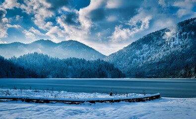 Beautiful lakeshore with mountains and a cloudy blue sky in the backgroun perfect for wallpapers