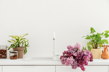 Fototapeta na wymiar Sink with lilac flowers in light kitchen