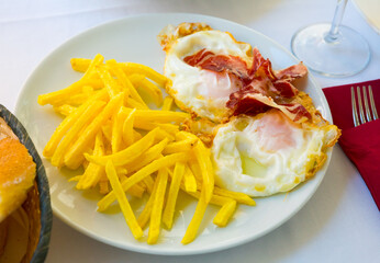 Spanish cuisine. Delicious broken eggs roasted with sliced Iberian ham and fried potatoes