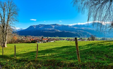 Beautiful view of the green field and village against the background of mountains. Bavaria, Germany.