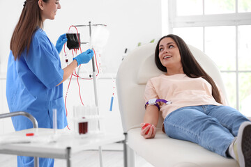 Female nurse preparing young donor for blood transfusion in clinic