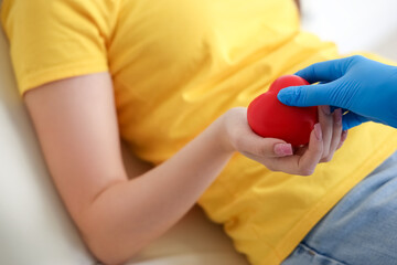 Female blood donor taking grip ball from nurse in clinic, closeup