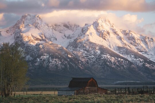 Small hut with the snowy peaks of the Grand Tetons mountains in the background during the daytime © Minrui Gu/Wirestock Creators