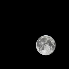 Fototapeta premium Pale full moon isolated on black background, close-up