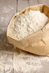 Paper bag with wheat flour on grey wooden background