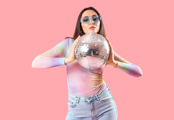 Fashionable beautiful woman in stylish sunglasses with disco ball on pink background