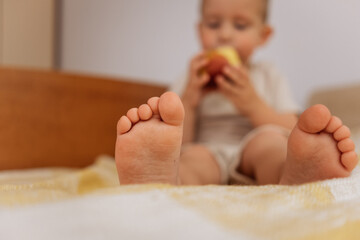 children's bare feet on the bed on a yellow blanket