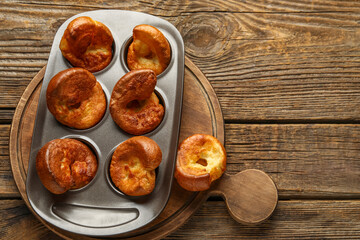 Baking tin with tasty Yorkshire pudding on wooden background