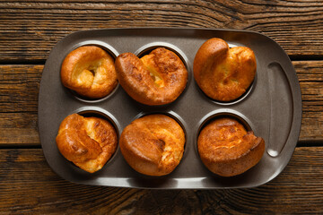 Baking tin with tasty Yorkshire pudding on wooden background