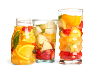 Fototapeta na wymiar Glasses of infused water with different sliced fruits on white background