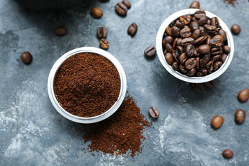 Bowls with coffee beans and powder on dark background