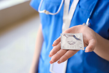 Female doctor with condom in clinic, closeup