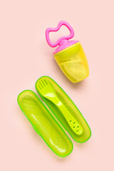 Eating utensils with nibbler for baby on pink background