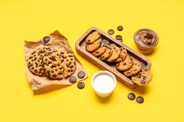 Cookies with chocolate and milk on yellow background