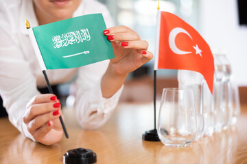 Little flag of Turkey on table with bottles of water and flag of Saudi Arabia put next to it by...