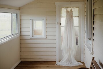 Beautiful lace wedding dress on a hanger hanging on a window