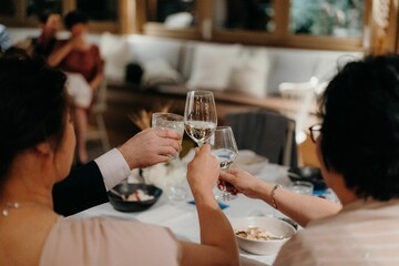Back view of people raising glasses for a toast on a wedding party