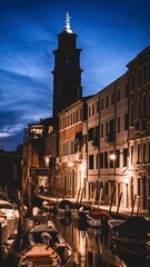 Vertical shot of illuminated buildings near the canal in the evening in Venice, Italy