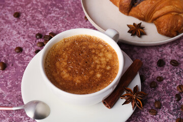 Obraz na płótnie Canvas Cup of delicious espresso with coffee beans and croissant on purple background, closeup