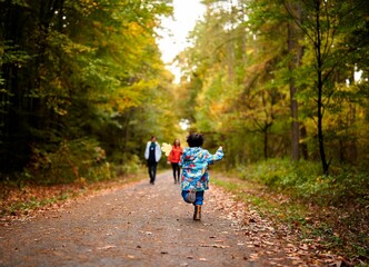 Little boy running towards family in autumn forest
