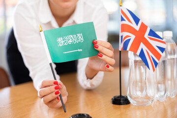 Little flag of Great Britain on table with bottles of water and flag of Saudi Arabia put next to it...