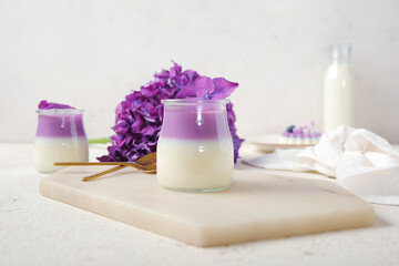 Obraz na płótnie Canvas Glasses of panna cotta with beautiful hydrangea flowers on white table