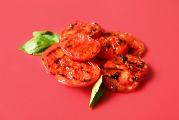 Tasty grilled tomatoes and basil on red background