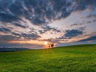 Naklejka premium Landscape of large meadows under dramatic sunset sky, perfect for background