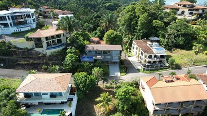 Fototapeta premium Drone view of villas in sunlight surrounded with green trees