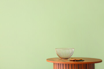 Wooden coffee table with metallic bowl near green wall