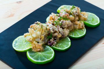 Fried squid and cuttlefish in batter served with sesame and herbs on marinated lime slices