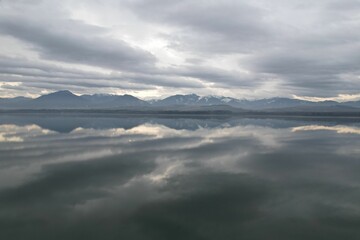 Scenic view of a lake and mountains with the reflection of low clouds on the waters
