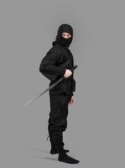 Male ninja with sword on grey background