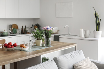 Island table with flowers and food in interior of light open space studio apartment