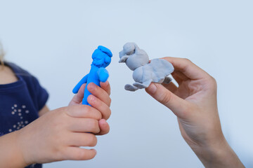 close-up plasticine colourful toys in hands children sculpt together animals, figures of characters from colourful dough, concept of fine motor skills, tactile sensations, creativity