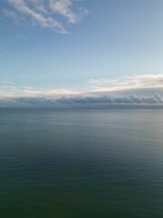 Fototapeta premium Vertical high-angle of a seascape with beach view with cloudy sky in the background