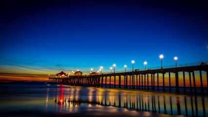 Obraz premium Fantastic view a bright sunset over an oceanside pier with lights
