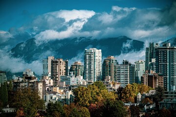 Scenic view of buildings and trees against a mountain range covered with clouds
