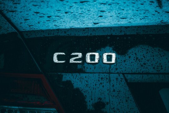 Closeup of a black Mercedes c200 logo detail on a rainy day