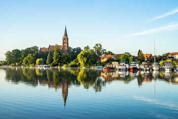 Fototapeta premium Beautiful shot of houses with trees on the riverside and boats docked in the foreground under sky