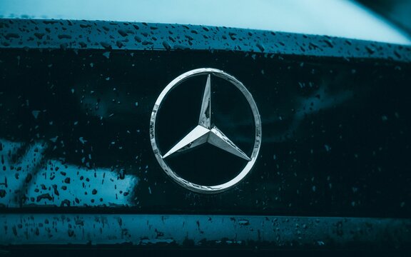 Closeup of the Mercedes c200 logo and emblem on the wet, blue trunk