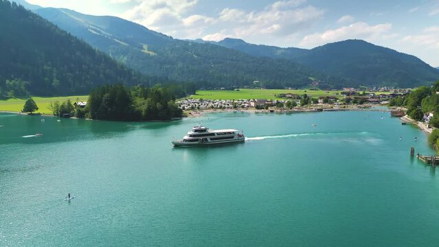 Aerial view of a boat sailing on the beautiful turquoise Lake Achen near the Alps in Austria