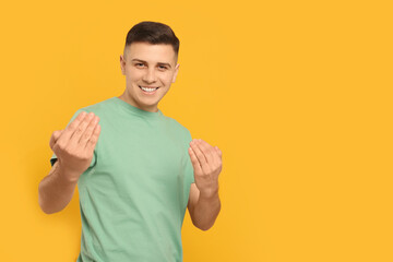 Handsome man inviting to come in against orange background. Space for text