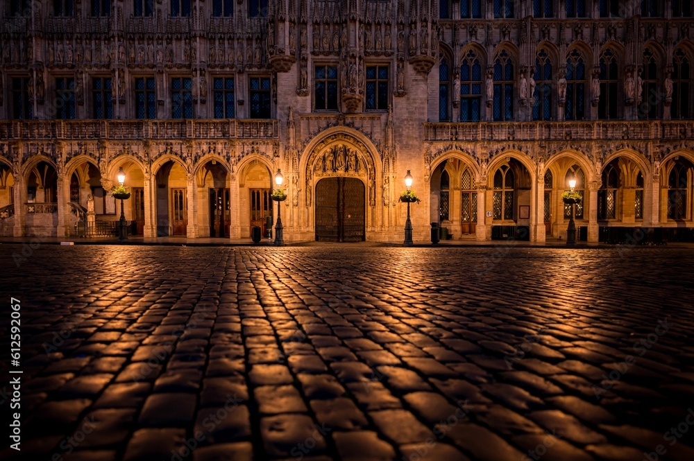 Sticker cobblestone street in front of a building at night in brussels town hall, belgium