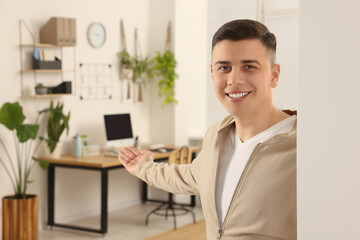 Handsome man inviting to come in room at home