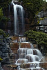 Vertical shot of the waterfall flowing over the rocks and stones