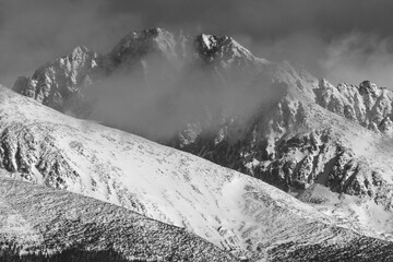 Stunning grayscale sho of snow-capped mountains in a serene winter setting