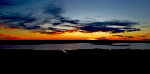 Panoramic shot of a scenic skyline with clouds over a lake at sunset